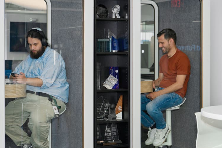 Two males sitting in two seperate booths