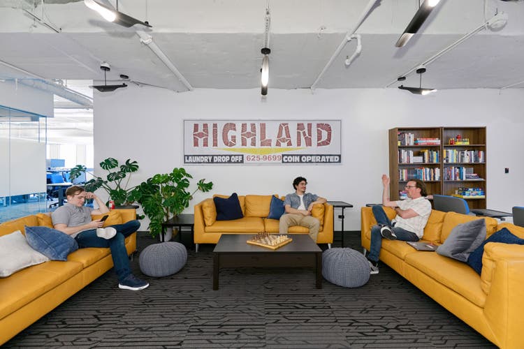 Three people sitting on sperate yellow couches in the office
